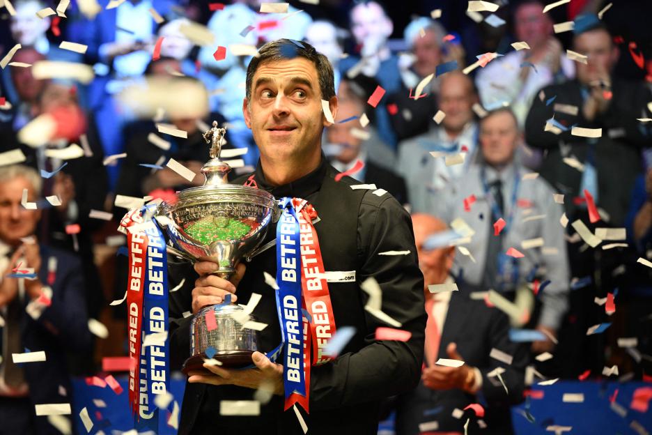 Ronnie O'Sullivan holding a snooker championship trophy.