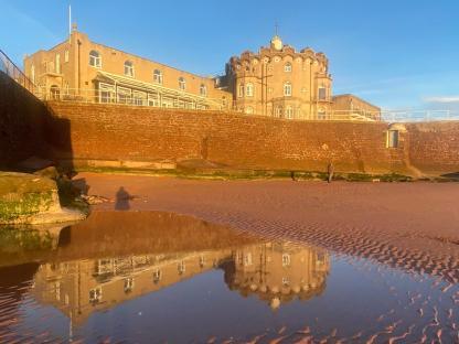Reflection of a building in a tidal pool on a sandy beach.