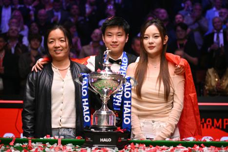 Zhao Xintong with his girlfriend and the head of the Sheffield Snooker Academy posing with the World Snooker Championship trophy.