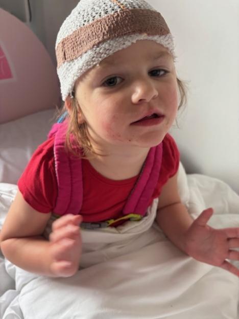 Teraysa, a three-year-old girl with Batten's disease, wearing a knitted cap and red shirt, looking at the camera.