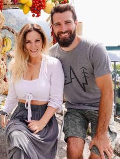 Couple posing in front of fruit and vegetable display in Italy.
