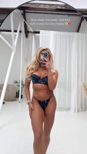 Woman in lingerie holding a phone in front of her face.