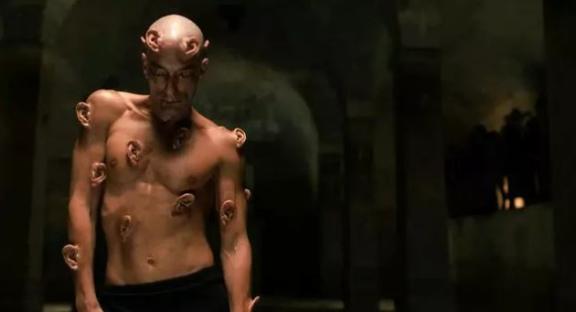 Still from Crimes of the Future showing a man with numerous ears attached to his body.