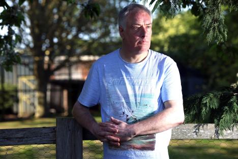 Man leaning on a fence, reflecting on the contaminated blood scandal.