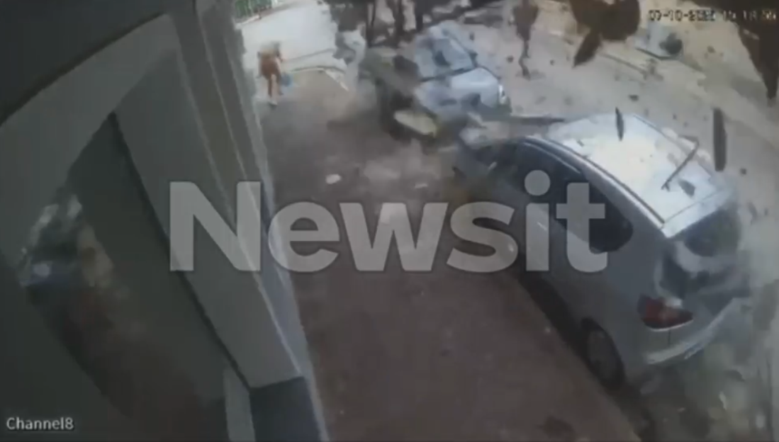 CCTV footage of an explosion causing debris and dust to fly, impacting two parked cars.
