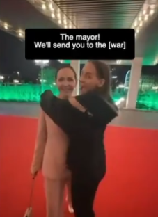 A woman embracing a life-sized cutout of the mayor on a red carpet.