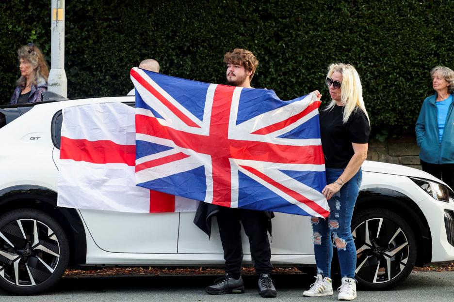 People holding Union Jack and St. George's flags at a demonstration.