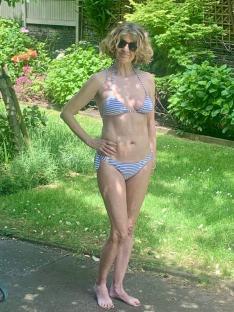 Woman in striped bikini in a garden.