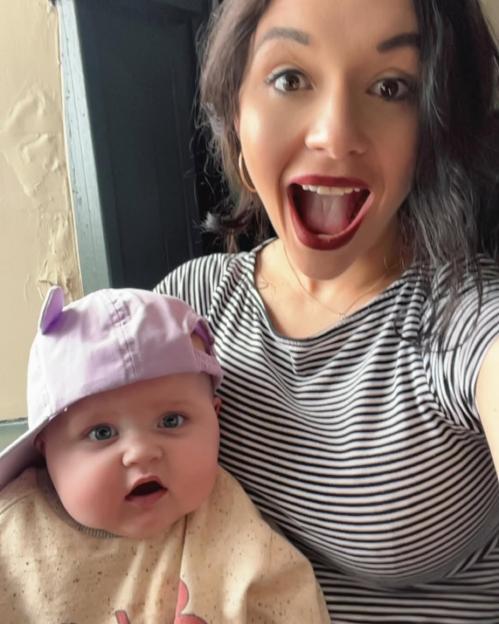 Woman holding baby wearing a purple hat.
