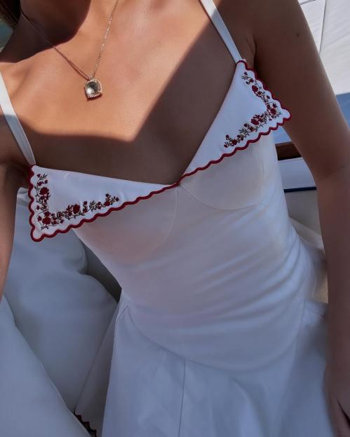 White dress with red floral embroidery.