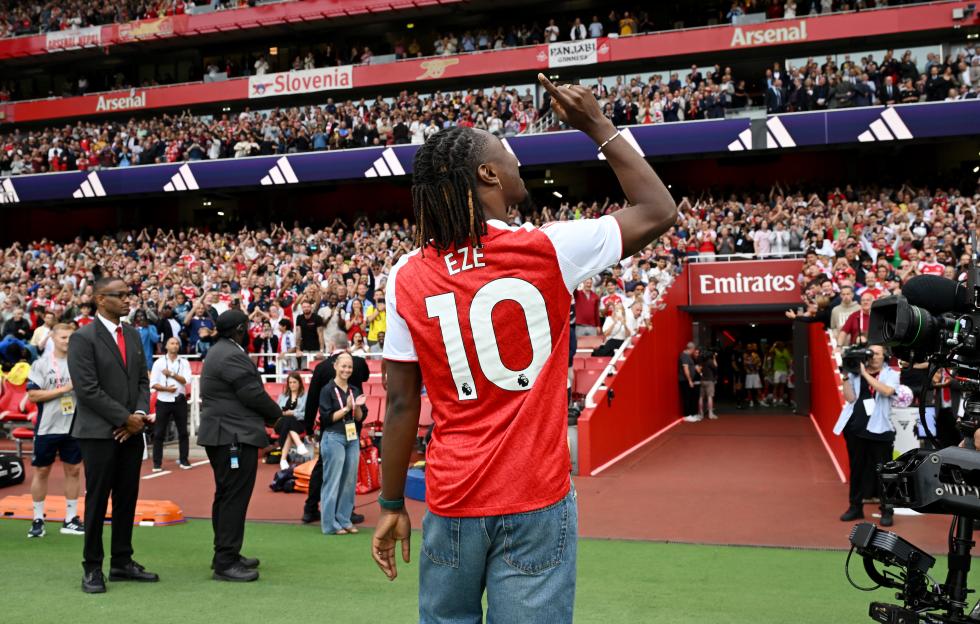 Eberechi Eze, wearing an Arsenal jersey, acknowledges fans before a Premier League match.