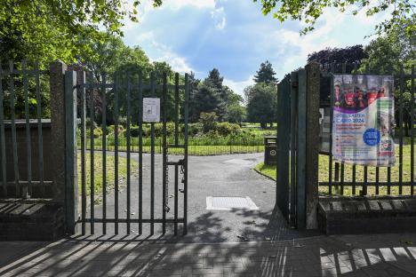 Locked gate to a park with a poster advertising a children's camp.
