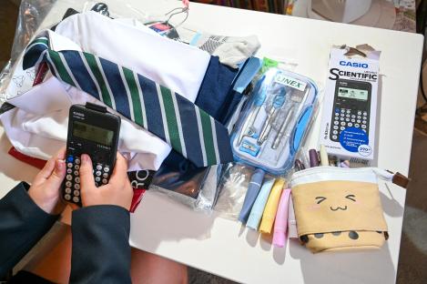 School uniform, stationery, and calculator laid out on a table.