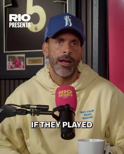 Rio Ferdinand wearing a blue cap and yellow hoodie, speaking into a microphone.