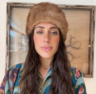 Portrait of Ariana Rodriguez wearing a fur hat and patterned shirt.