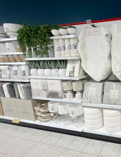 Store shelf display of home goods in white and beige tones.
