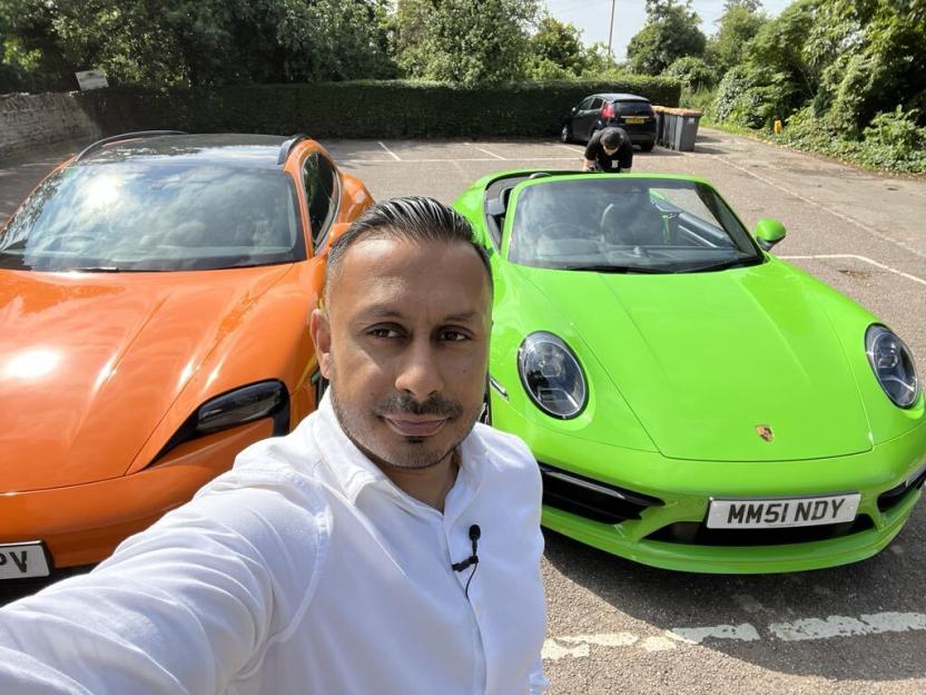 Self-made millionaire posing with two luxury cars.