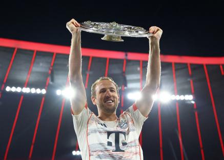 Harry Kane of Bayern Munich holding the Bundesliga trophy aloft.