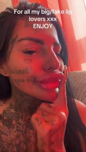 Close-up of a person with large lips and face tattoos.