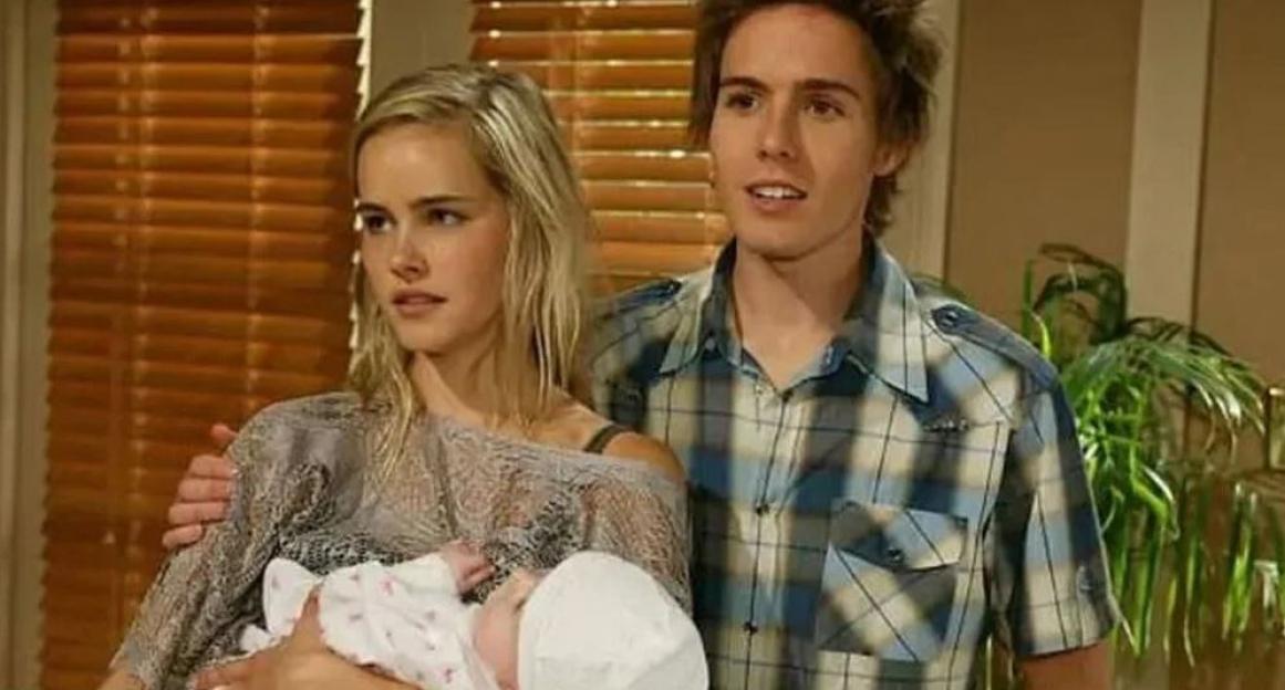 Isabel Lucas holding a baby with a man standing next to her.