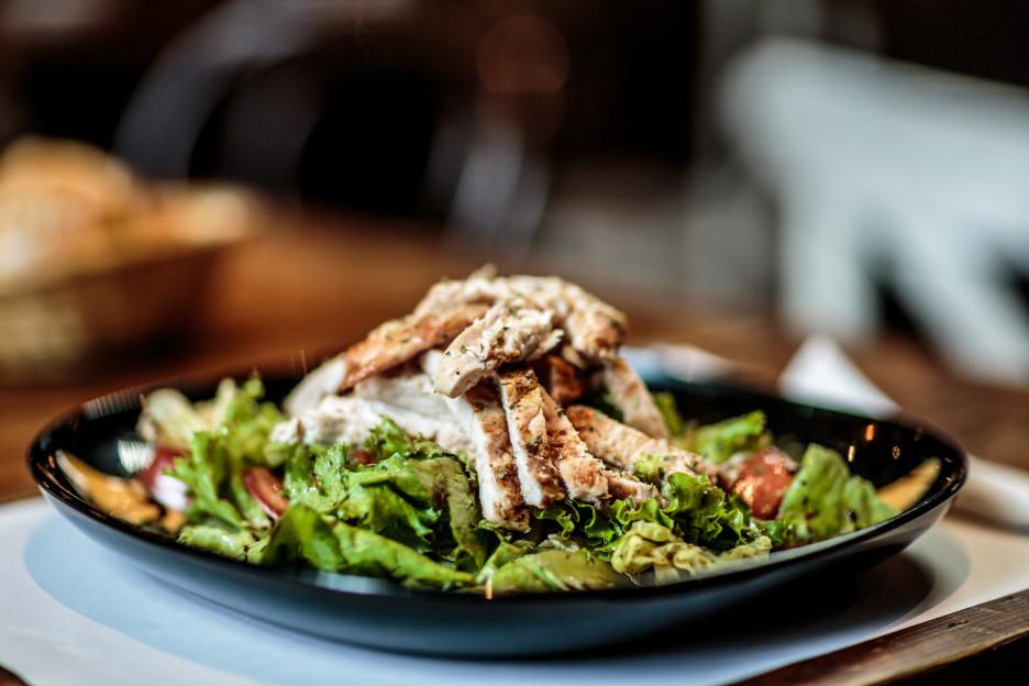 Grilled chicken salad on a black plate.