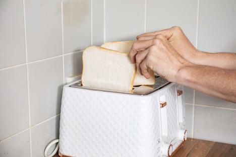 A person placing slices of bread into a toaster.
