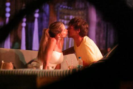 Louis Tomlinson and Zara McDermott kissing at a table.