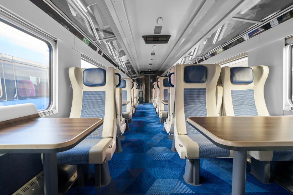 Interior of a modern train car with tables and seats.