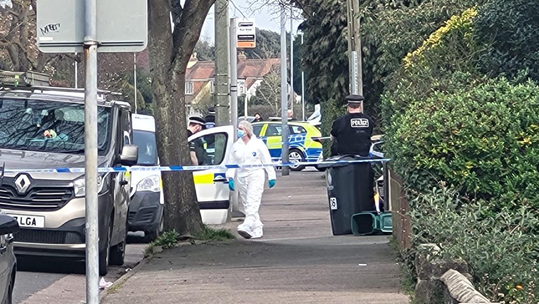A murder investigation in Clacton-on-Sea with a person in a white forensic suit and police present.