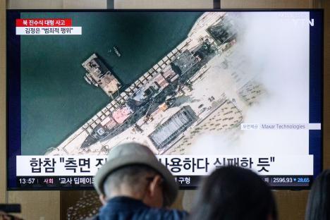 Television screen showing satellite image of North Korean warship launch accident.