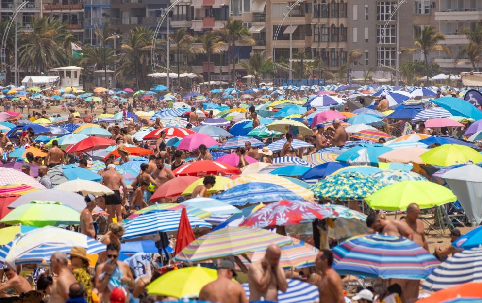 Crowded beach in Las Palmas, Gran Canaria with many colorful umbrellas.