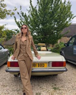 Juliet Angus, a stylist from Ladies of London, leaning against a vintage car.