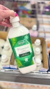 A hand holding a bottle of Almat Premium Fabric Conditioner, Sea Salt & Driftwood.