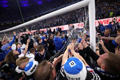 Fans celebrating a soccer team's promotion by ripping down the goal net.