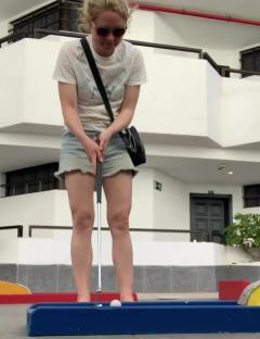 Woman putting a golf ball on a miniature golf course.