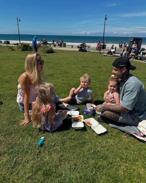 Family having a picnic on the grass by the beach.