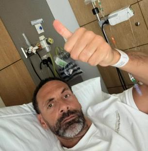Man in hospital bed giving thumbs up.