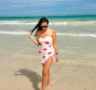 Woman in floral dress walking on beach.