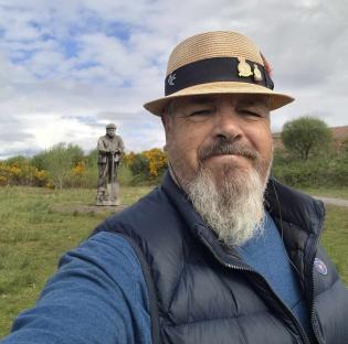 Selfie of a man with a statue in the background.