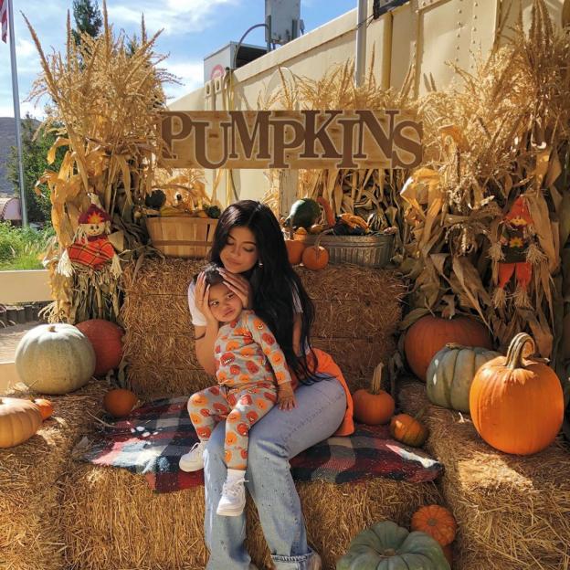 Kylie Jenner holding her daughter Stormi in a pumpkin patch.