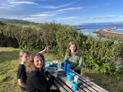 Family enjoying a meal outdoors overlooking the coast.