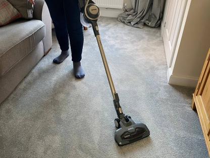 Person vacuuming carpet with a Beldray Airgility cordless vacuum.
