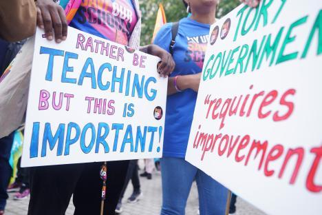 Protestors holding signs about teacher pay and the Tory government.