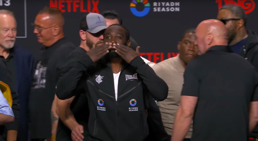 Screenshot of a boxer covering his face with his hands at a press conference.