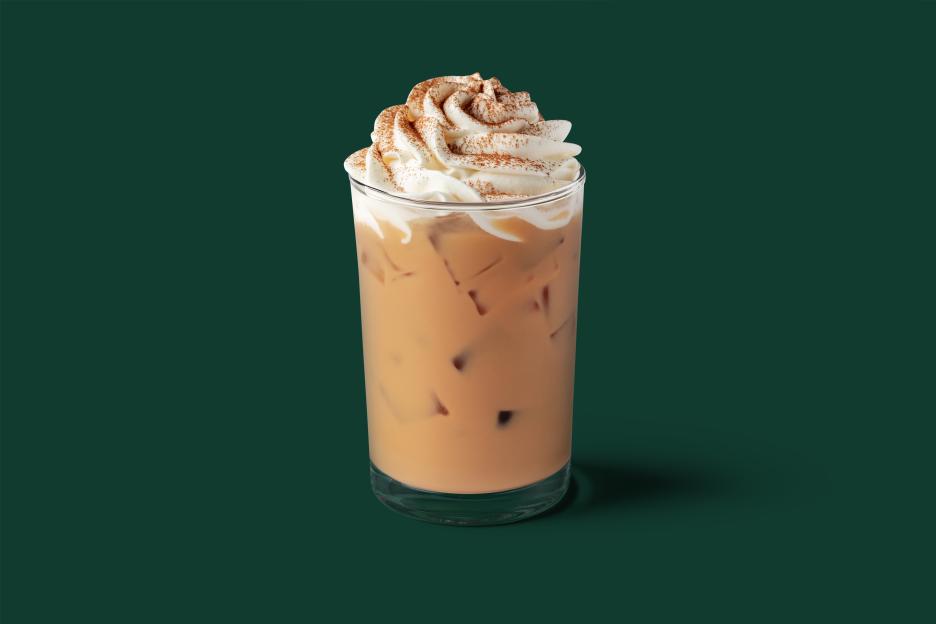 Iced pumpkin spice latte with whipped cream and a sprinkle of spices on top.