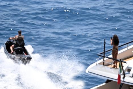Maya Jama and Ruben Dias on a yacht; he's jetskiing while she takes photos.