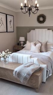Bedroom with white upholstered bed, beige bedding, and wooden bench.