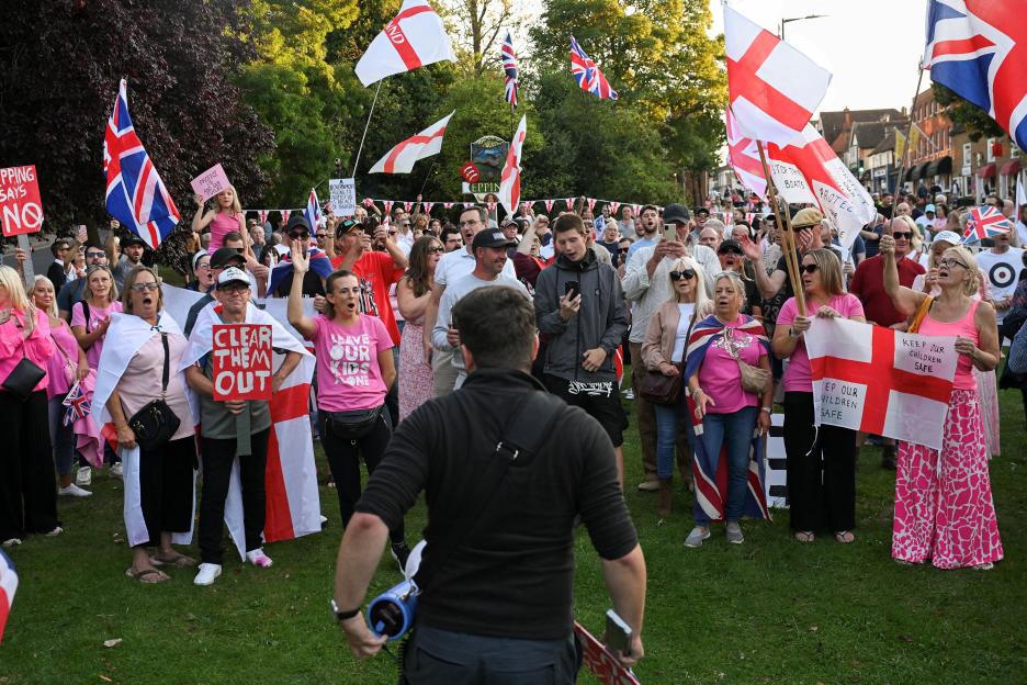 Protesters at an anti-immigration demonstration hold signs and flags.