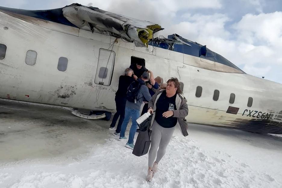 Passengers leaving a crashed Delta Air Lines CRJ-900 jet in the snow.