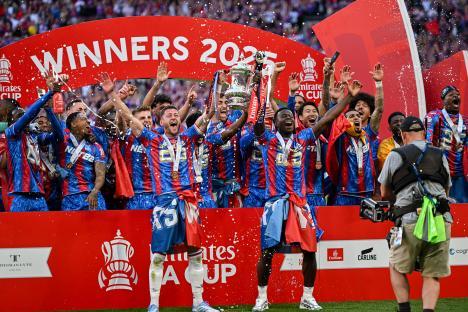 Soccer players celebrating with the Emirates FA Cup trophy.